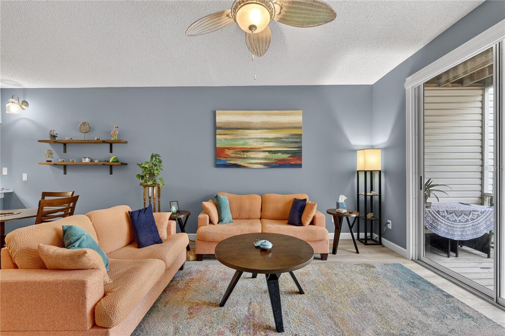 A living room features two orange sofas, a round coffee table, and a sliding glass door — 320 ISLAND WAY UNIT 603, CLEARWATER, FL