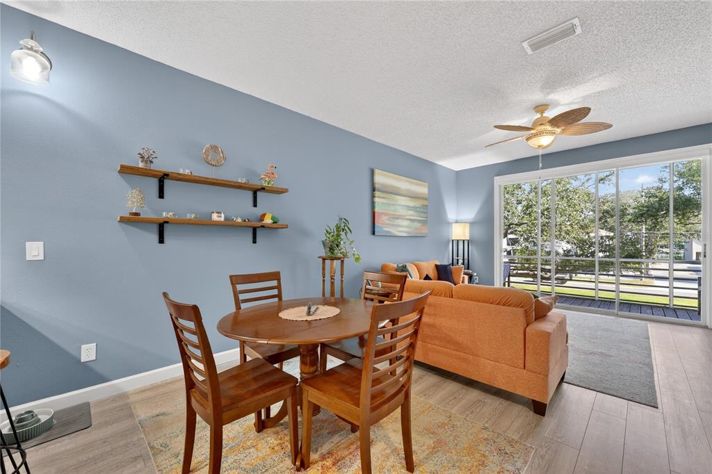 A dining area with a wooden table and chairs sits next to an orange sofa — 320 ISLAND WAY UNIT 603, CLEARWATER, FL