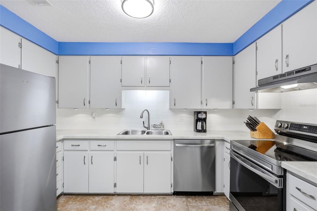A kitchen with gray cabinets, stainless steel appliances, white countertops, and a blue accent wall — 411 S BROOKS AVENUE, DELAND, FL