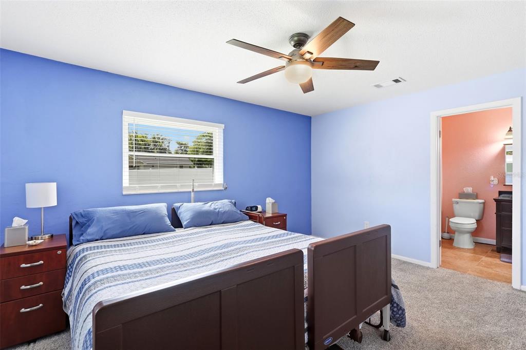 A bedroom features a dark wood bed frame, blue accent wall, and an attached bathroom — 411 S BROOKS AVENUE, DELAND, FL