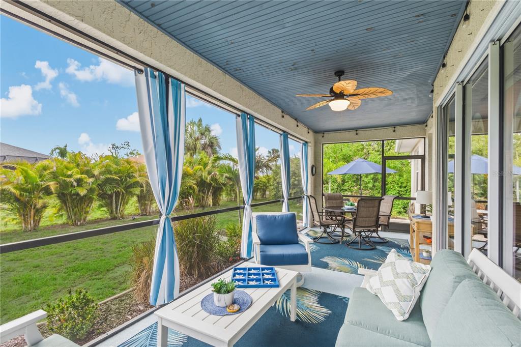 A screened-in porch features a blue ceiling, a ceiling fan, and outdoor furniture — 117 BEAU RIVAGE DRIVE, ROTONDA WEST, FL