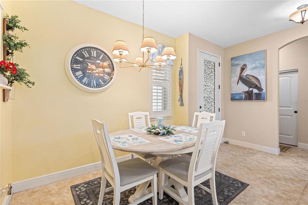A dining area features a round wooden table, four white chairs, and a wall clock — 117 BEAU RIVAGE DRIVE, ROTONDA WEST, FL