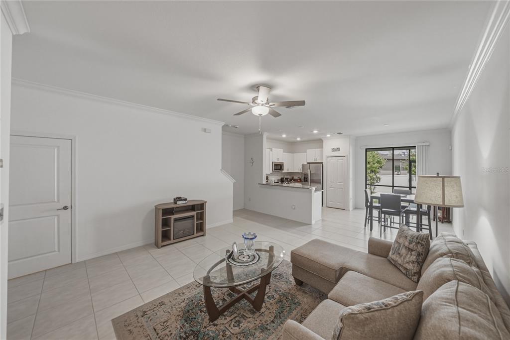 A view from a hallway looking into an open-concept living room and kitchen area — 30688 VERIDIAN WAY, WESLEY CHAPEL, FL