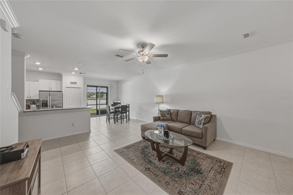 A living room with tile floors, a ceiling fan, and an open kitchen in the background — 30688 VERIDIAN WAY, WESLEY CHAPEL, FL