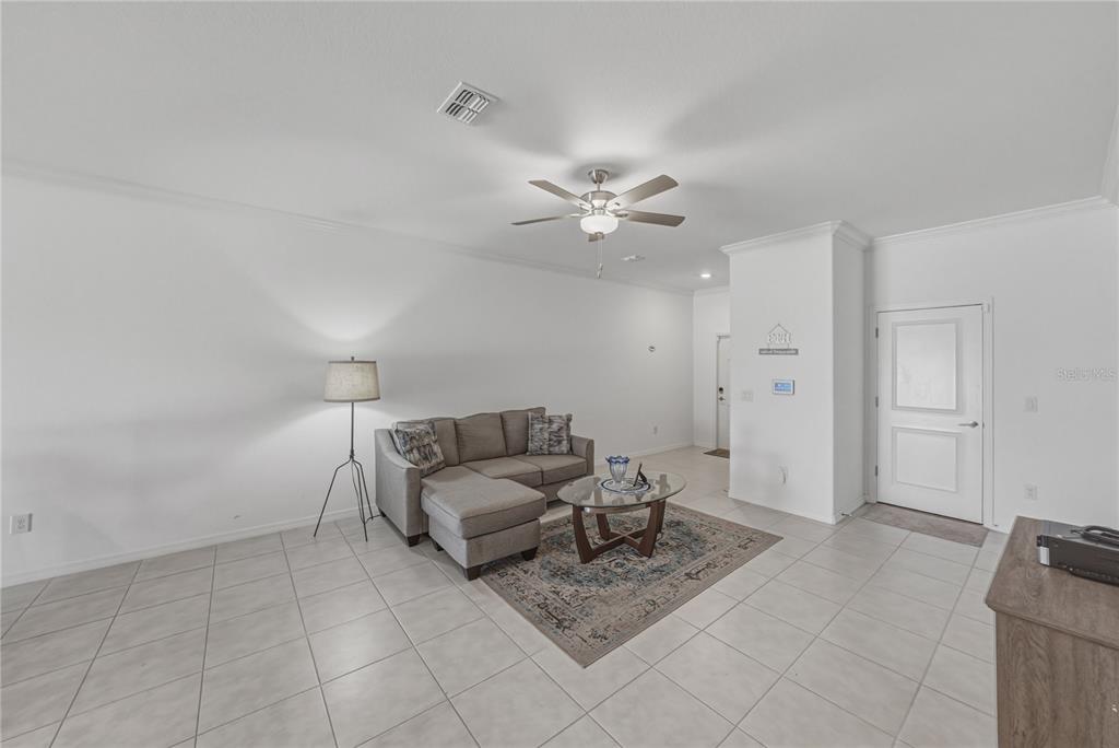 An open-concept living room and kitchen featuring tile flooring, a ceiling fan, and neutral walls — 30688 VERIDIAN WAY, WESLEY CHAPEL, FL