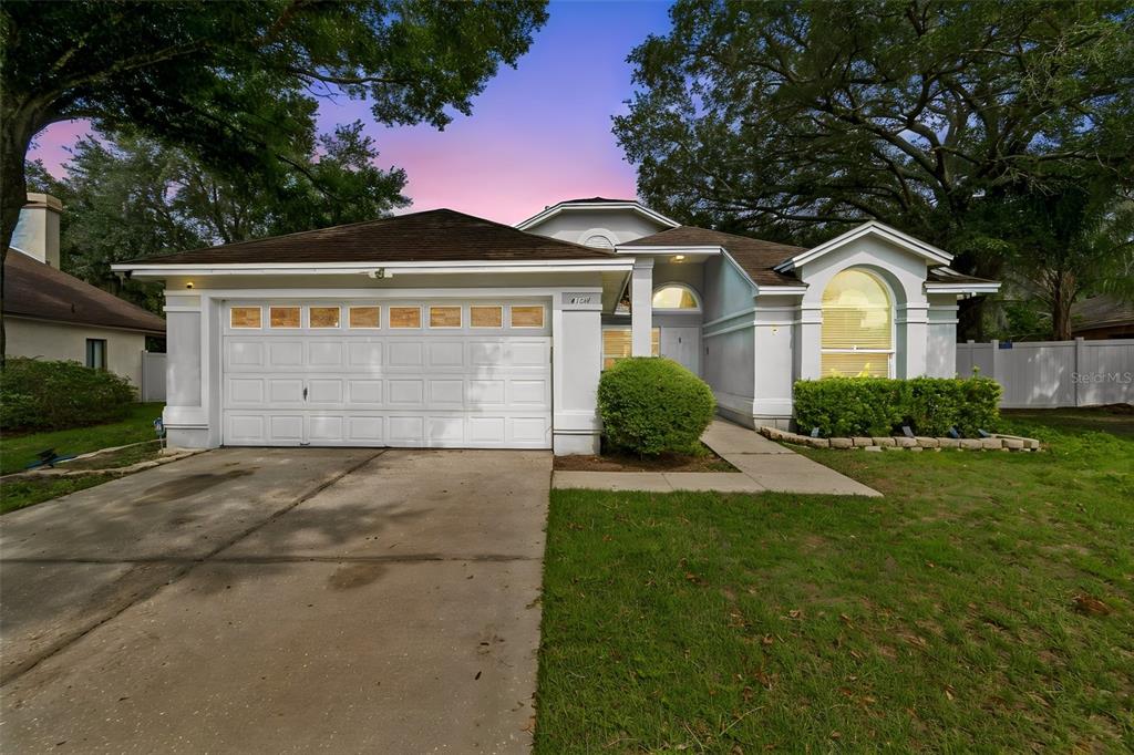 A single-story house with a white garage, arched window, and a concrete driveway — 4133 BARRET AVENUE, PLANT CITY, FL