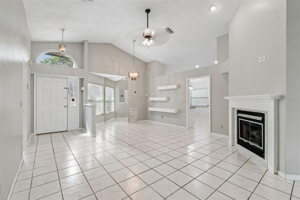 A living room features white tile floors, a vaulted ceiling, a fireplace, and floating shelves — 4133 BARRET AVENUE, PLANT CITY, FL