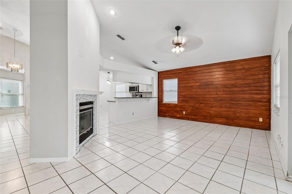 A living room with white tile floors, a fireplace, and a wood-paneled accent wall — 4133 BARRET AVENUE, PLANT CITY, FL
