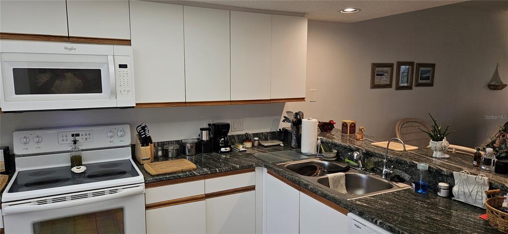 A kitchen features white cabinets, dark granite countertops, and a white electric range — 2320 TERRA CEIA BAY BOULEVARD UNIT 403, PALMETTO, FL