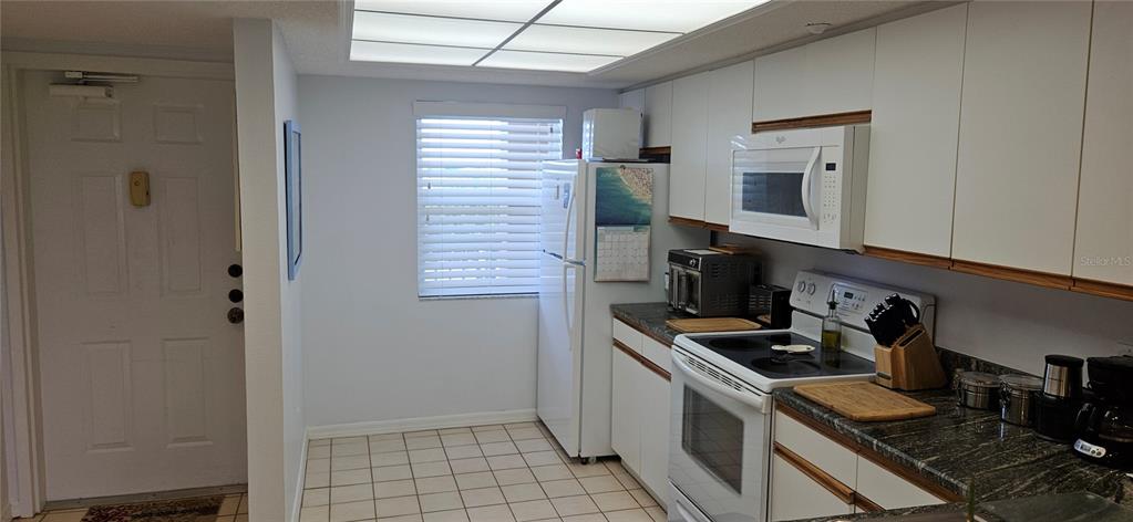 A kitchen features white cabinets, a white refrigerator, a white stove, and tiled flooring — 2320 TERRA CEIA BAY BOULEVARD UNIT 403, PALMETTO, FL