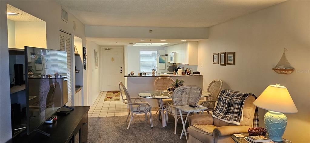 A living and dining area features a glass table, wicker chairs, and a kitchen counter — 2320 TERRA CEIA BAY BOULEVARD UNIT 403, PALMETTO, FL