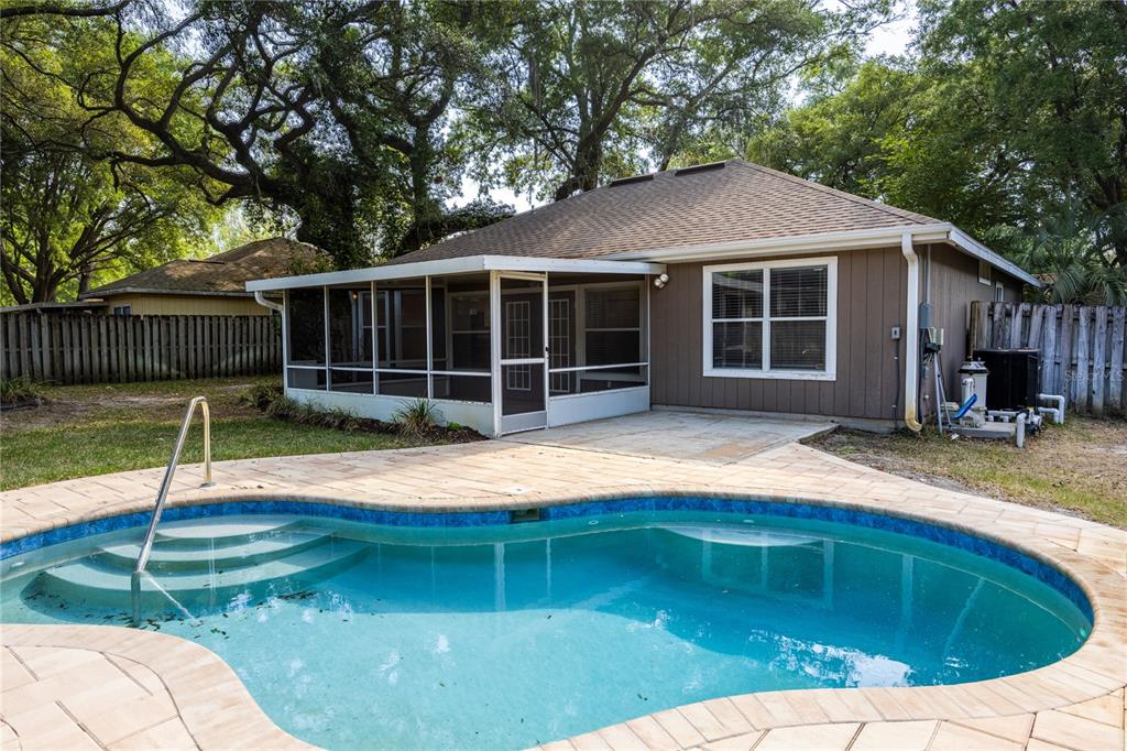 A backyard features a swimming pool with a paved deck and a screened-in patio area — 4511 NW 35TH STREET, GAINESVILLE, FL