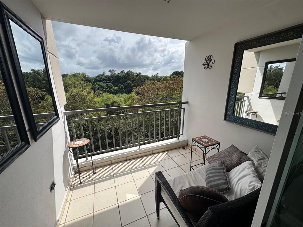 A balcony with tile flooring, a seating area, and a view of trees — Carr. 199 PASEO DEL BOSQUE UNIT 3-507, SAN JUAN, PR