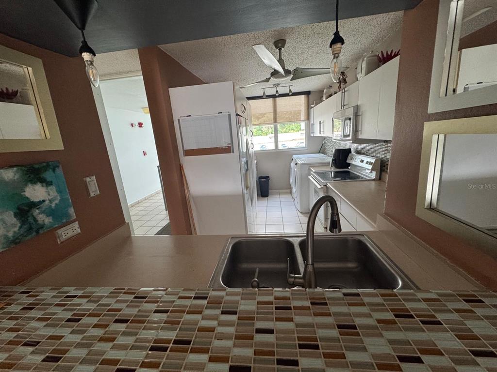 A kitchen features a double-basin sink, tiled countertop, white cabinetry, and a laundry area — Carr. 199 PASEO DEL BOSQUE UNIT 3-507, SAN JUAN, PR