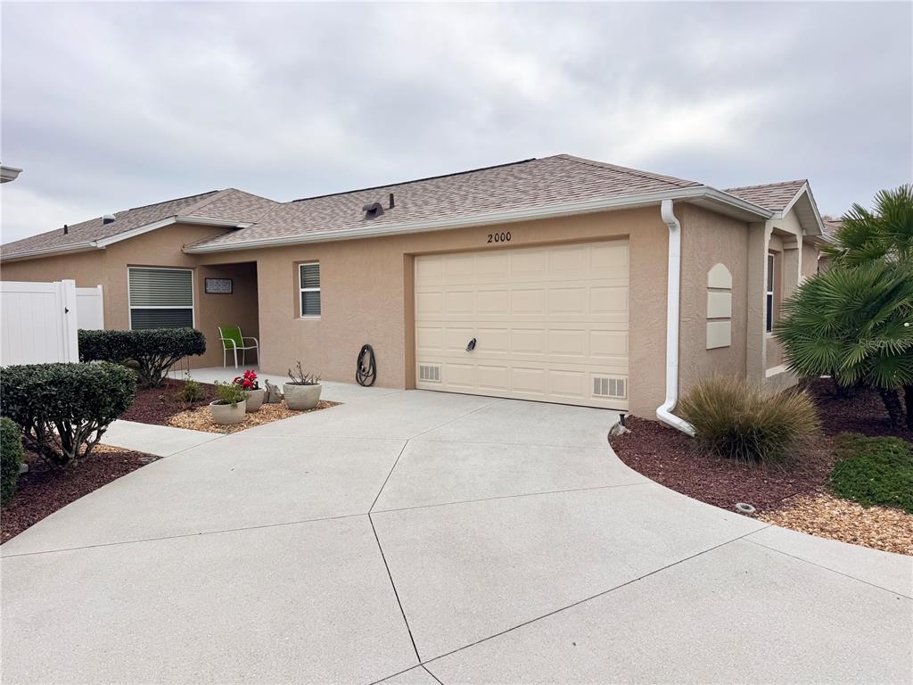 A tan, single-story house with a two-car garage and a concrete driveway — 2000 GOLDENROD COURT, THE VILLAGES, FL