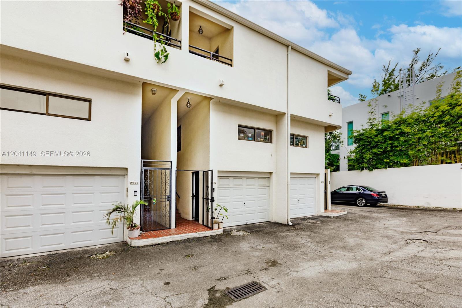 The exterior view shows a multi-story white building with three garage doors and a gated entrance — 2956 Bird Ave # 6, Miami FL 33133, MIAMI, FL
