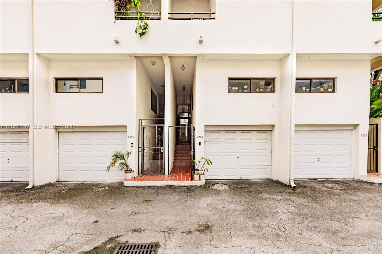The exterior view shows a multi-unit residential building with white stucco walls and garage doors — 2956 Bird Ave # 6, Miami FL 33133, MIAMI, FL