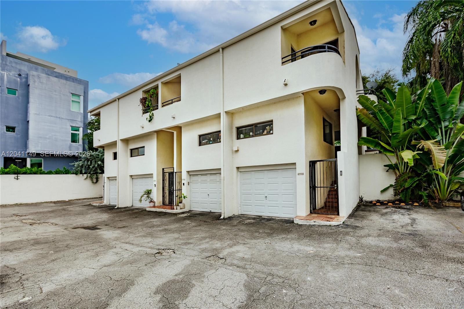 A multi-unit residential building features white stucco walls, garage doors, and a small balcony — 2956 Bird Ave # 6, Miami FL 33133, MIAMI, FL