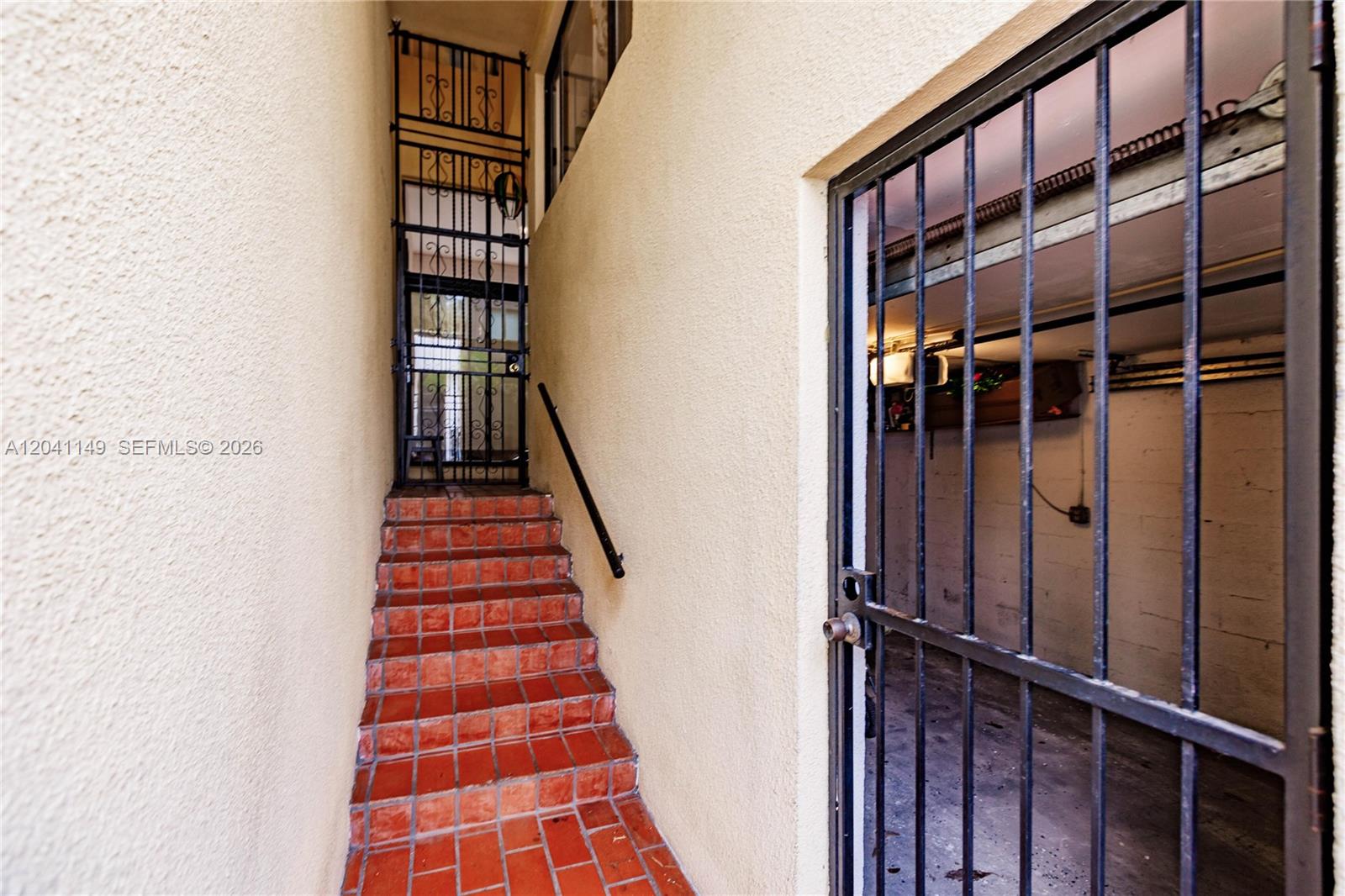 A narrow outdoor staircase with red tile steps leads to a metal security gate — 2956 Bird Ave # 6, Miami FL 33133, MIAMI, FL