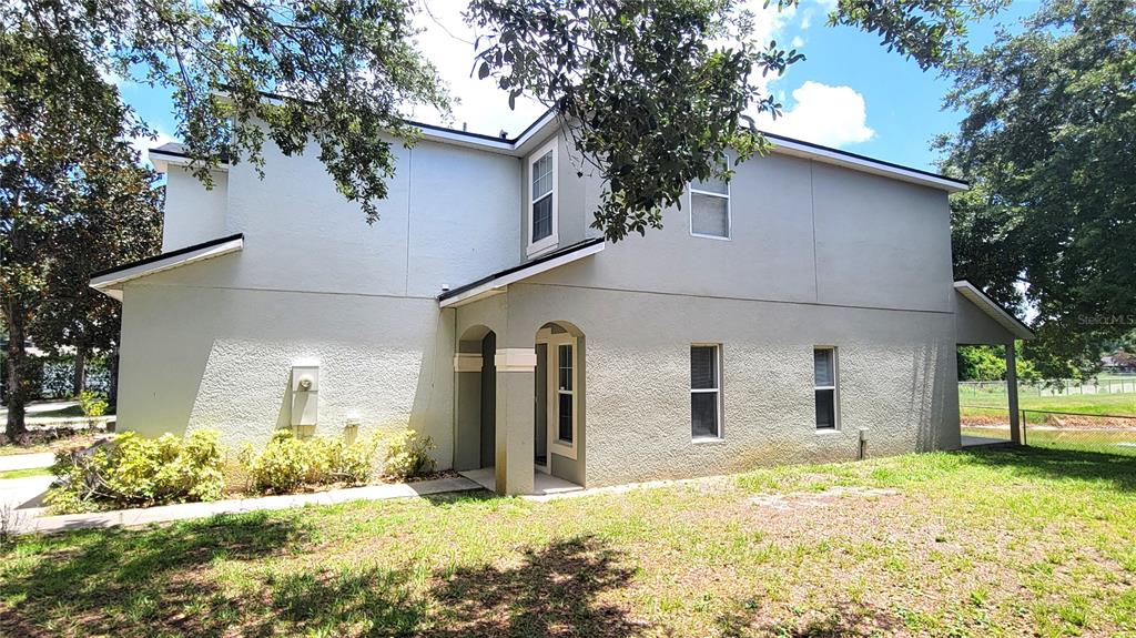 The exterior of a two-story stucco house features a covered entryway and several windows — 3871 CLUBSIDE POINTE DRIVE, ORLANDO, FL