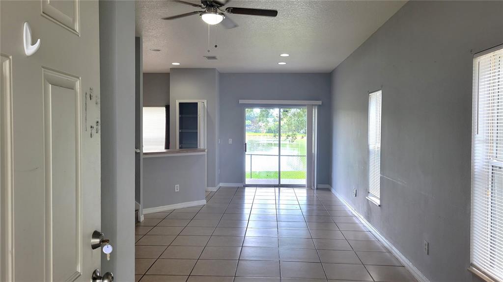 A tiled living area features a ceiling fan, sliding glass doors, and a lake view — 3871 CLUBSIDE POINTE DRIVE, ORLANDO, FL
