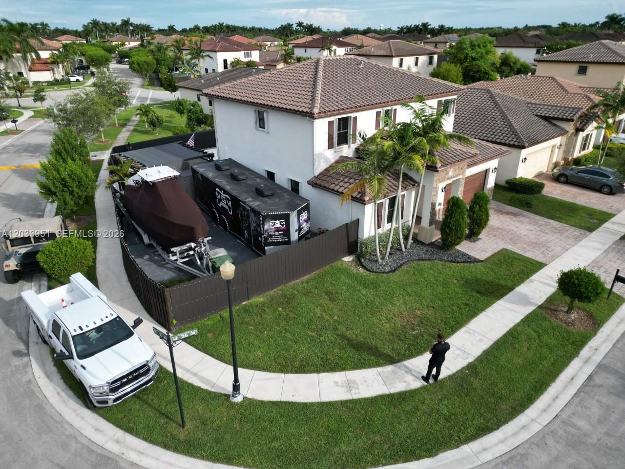 An aerial view shows a two-story house with a boat and trailer parked alongside — 175 NE 26th Ave, Homestead FL 33033, HOMESTEAD, FL