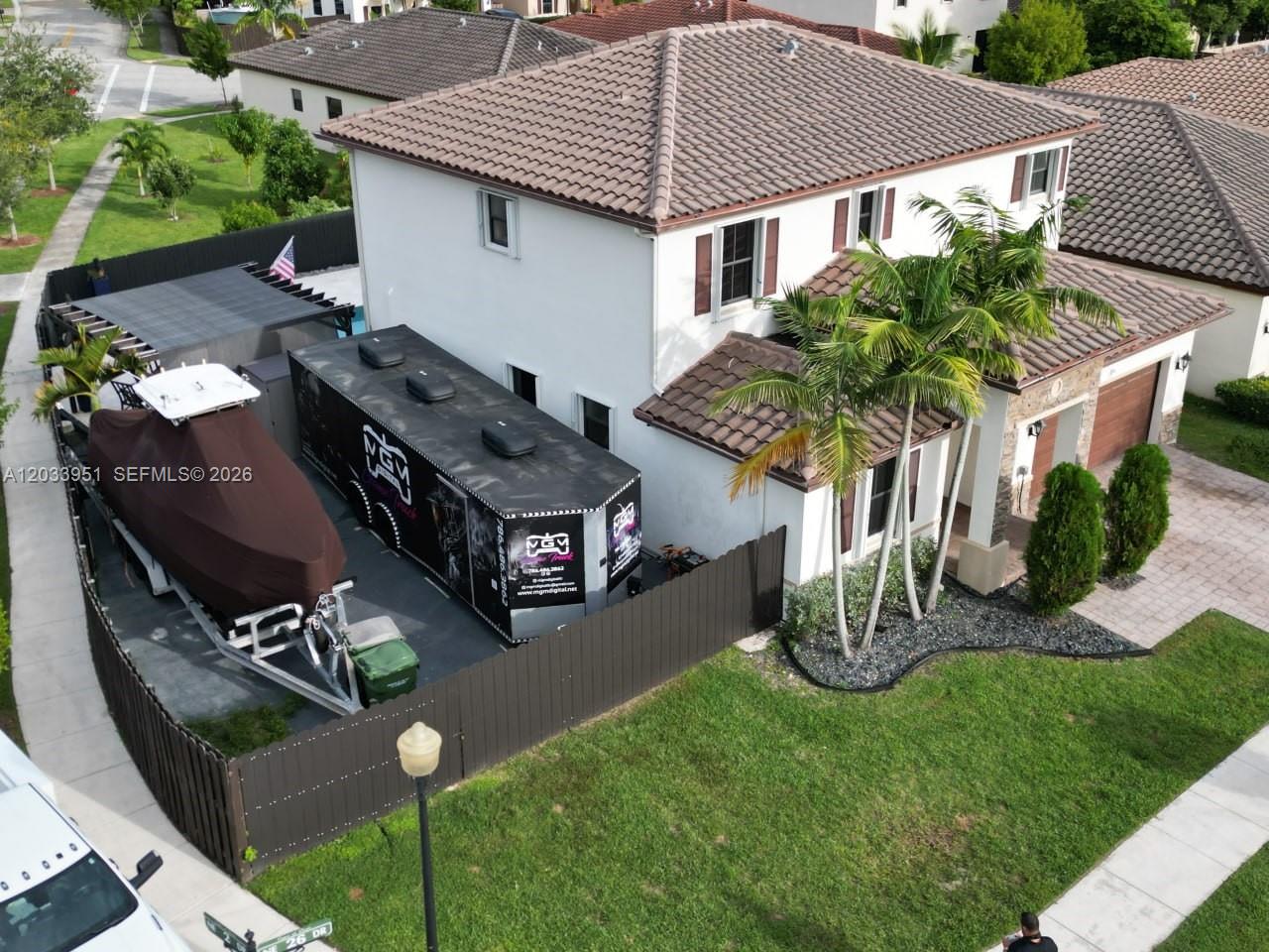 An aerial view shows a two-story house with a boat and trailer parked inside — 175 NE 26th Ave, Homestead FL 33033, HOMESTEAD, FL