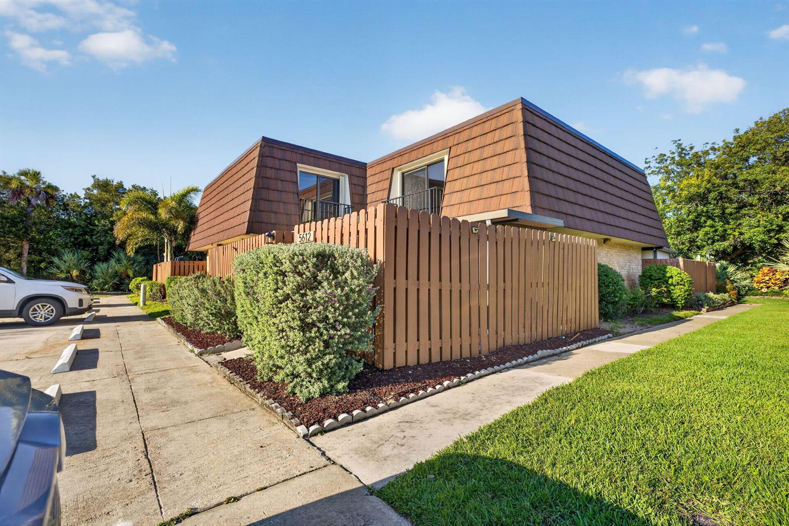 A two-story building with a brown mansard roof and a wooden privacy fence — 5612 SE Riverboat Drive # 104, Stuart FL 34997, STUART, FL
