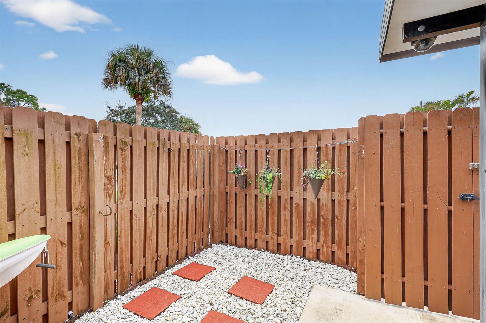 A small outdoor patio enclosed by a wooden fence with gravel and red stepping stones — 5612 SE Riverboat Drive # 104, Stuart FL 34997, STUART, FL