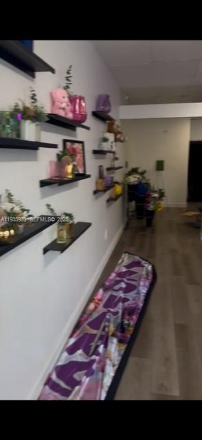 A hallway features multiple black floating shelves mounted on a white wall above wood flooring — 4090 NW 167th St, Miami FL 33054, MIAMI, FL