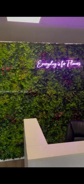 A reception desk sits in front of a green wall with a neon sign — 4090 NW 167th St, Miami FL 33054, MIAMI, FL