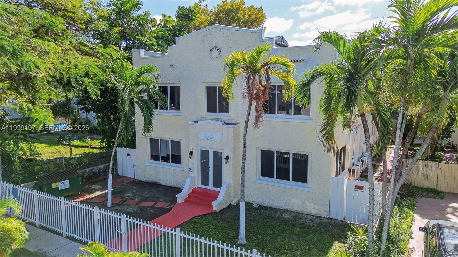An exterior view of a two-story, pale yellow apartment building with a red entryway — 1630 SW 10th St, Miami FL 33135, MIAMI, FL