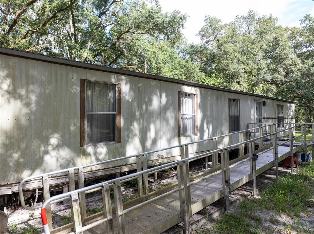 An exterior view of a mobile home with a metal wheelchair ramp leading to the entrance — 214 SW LEONARD TERRACE, LAKE CITY, FL