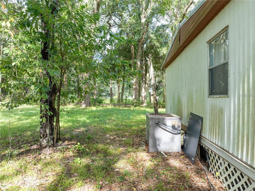 The exterior of a mobile home features a metal siding wall, a window, and an HVAC unit — 214 SW LEONARD TERRACE, LAKE CITY, FL