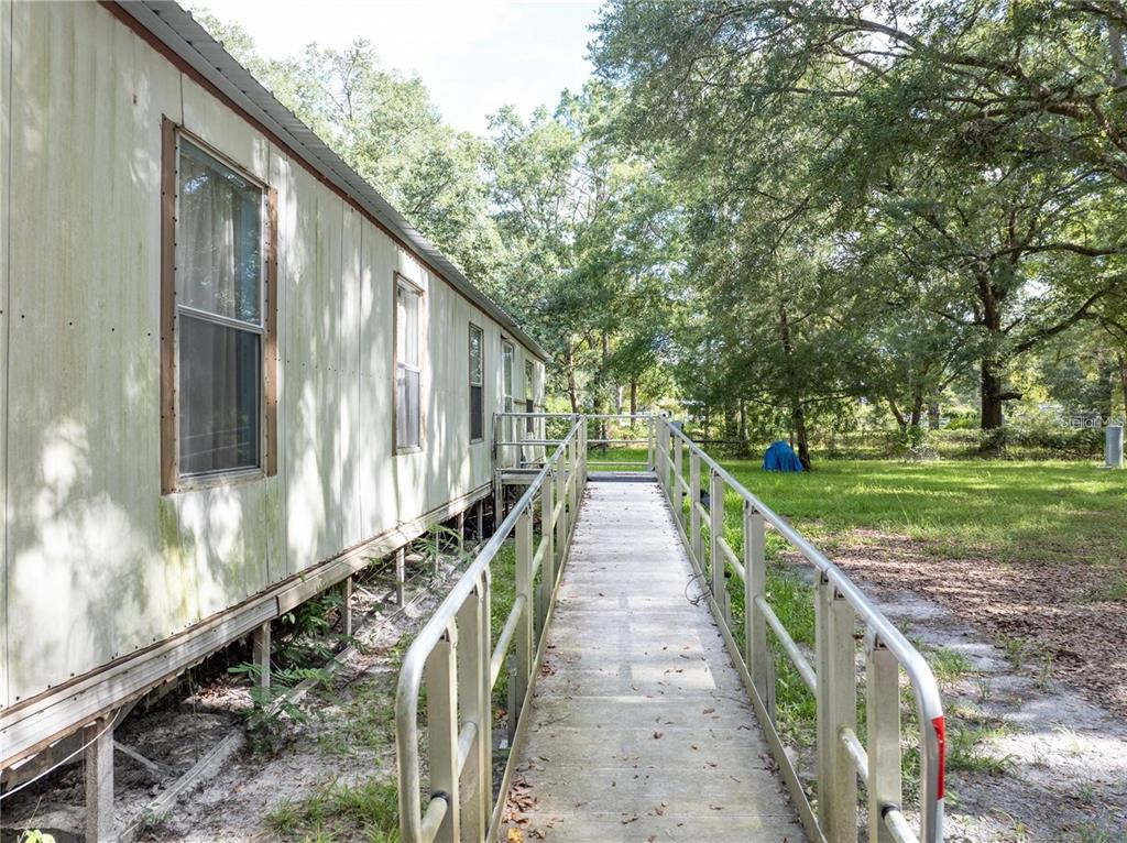 An exterior view of a mobile home with a metal wheelchair ramp leading to the entrance — 214 SW LEONARD TERRACE, LAKE CITY, FL