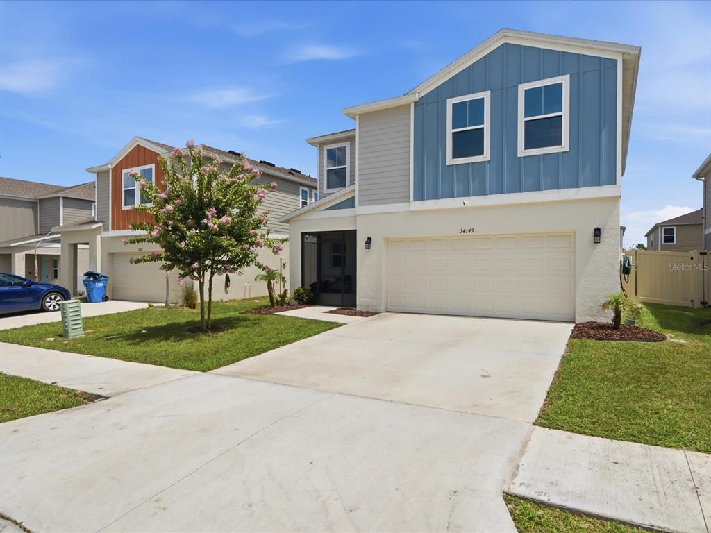 A two-story suburban house features a blue and beige exterior with a two-car garage — 34149 SCARLET SAGE COURT, WESLEY CHAPEL, FL