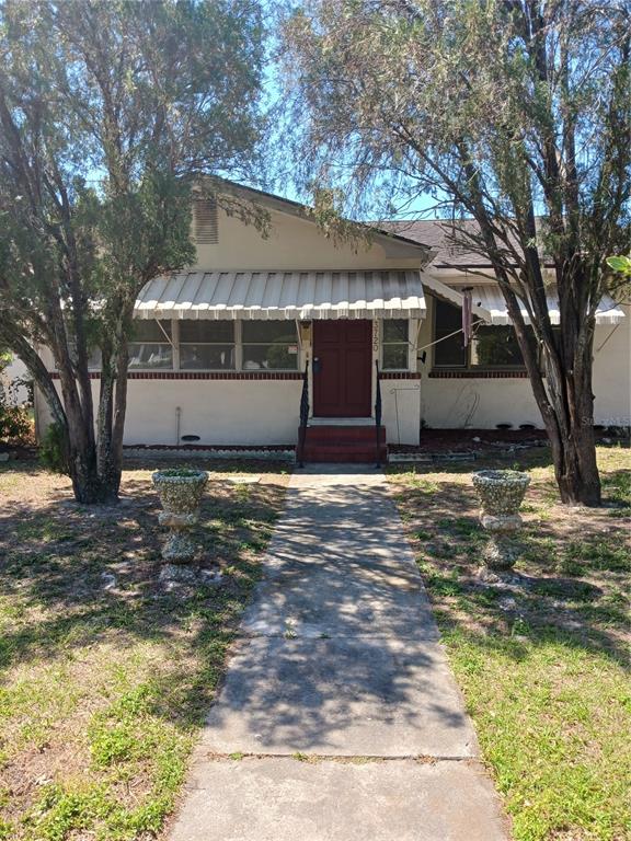 A single-story house with a white exterior, metal awnings, and a central front door — 3720 4TH AVENUE N, ST PETERSBURG, FL