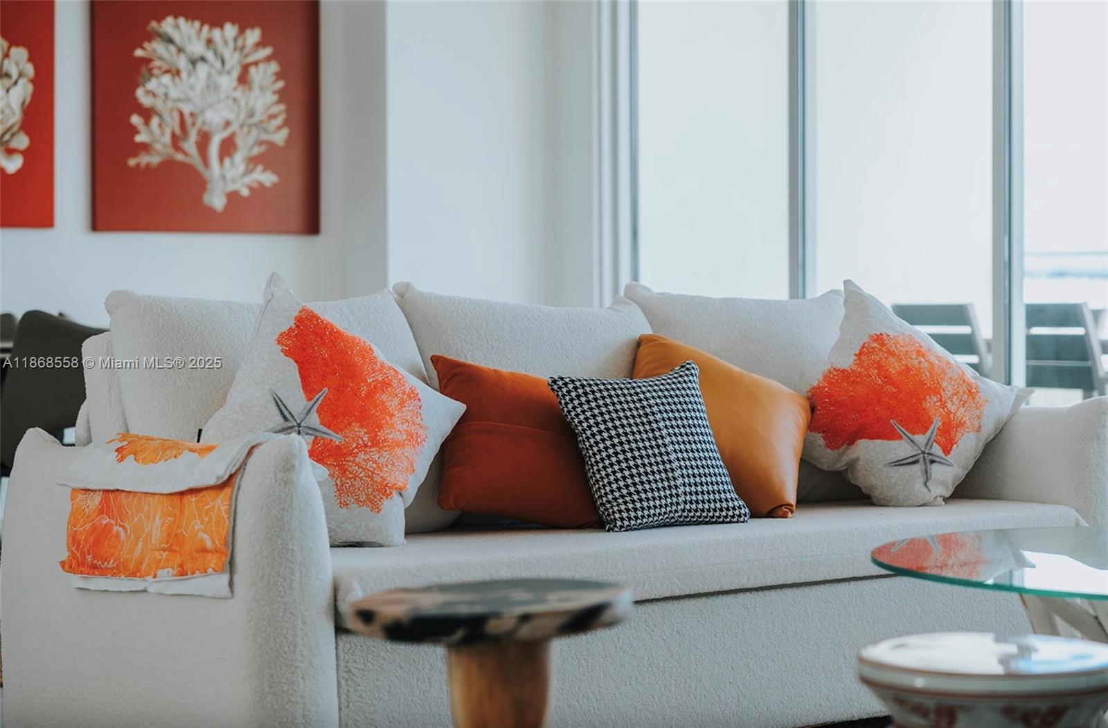 A white sofa with coral-themed and patterned pillows sits in a bright living room — 1 Irausquin Blvd Eagle beach Aruba # 4B, Ar, Ar