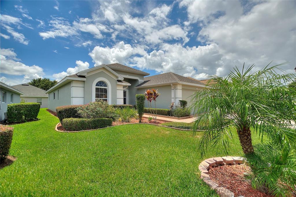 A single-story house with a light-colored exterior, a manicured lawn, and a small palm tree — 3923 BALDWIN LANE, WINTER HAVEN, FL