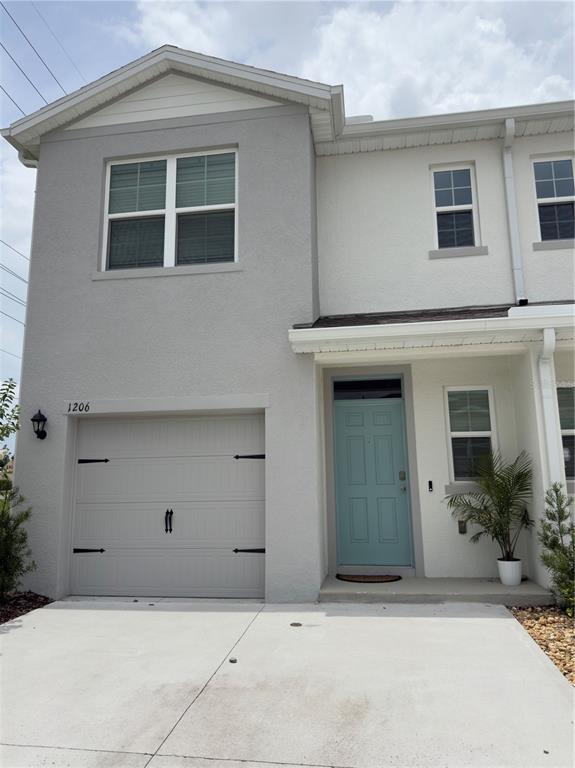 The exterior of a two-story townhouse features a gray garage, a light blue door, and white siding — 1206 BALSAM DRIVE, DAVENPORT, FL