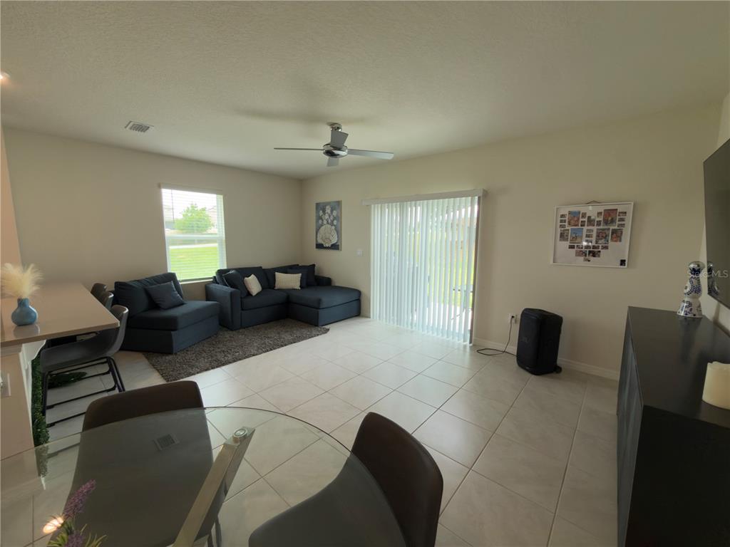 A living room features tile floors, a dark blue sectional sofa, and a sliding glass door — 1206 BALSAM DRIVE, DAVENPORT, FL
