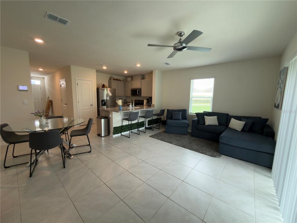 An open-concept living area features a kitchen with a breakfast bar, dining table, and sofa — 1206 BALSAM DRIVE, DAVENPORT, FL