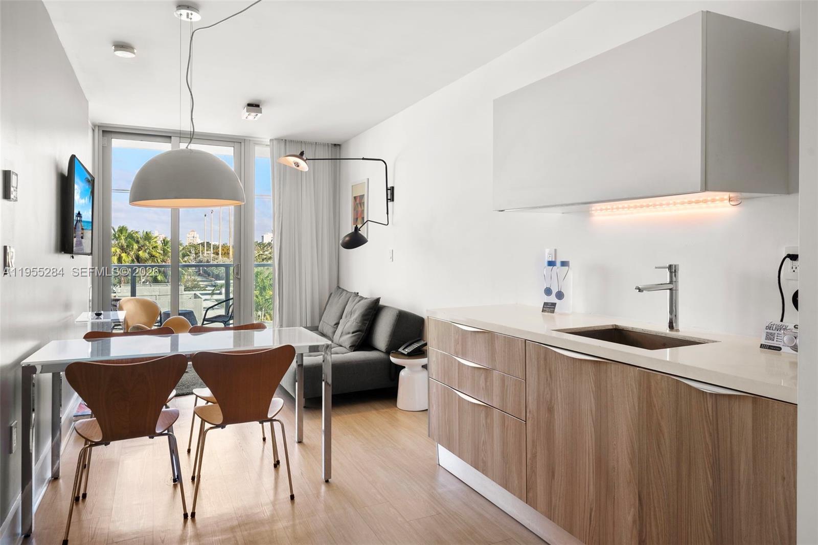 A modern studio apartment features a kitchenette, dining area, and a sofa near a balcony — 1215 West Ave # 408, Miami Beach FL 33139, MIAMI BEACH, FL