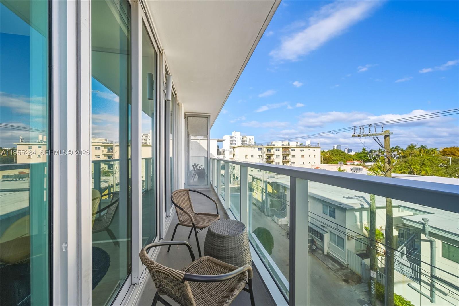 A balcony with two wicker chairs and a small table overlooks a city street — 1215 West Ave # 408, Miami Beach FL 33139, MIAMI BEACH, FL
