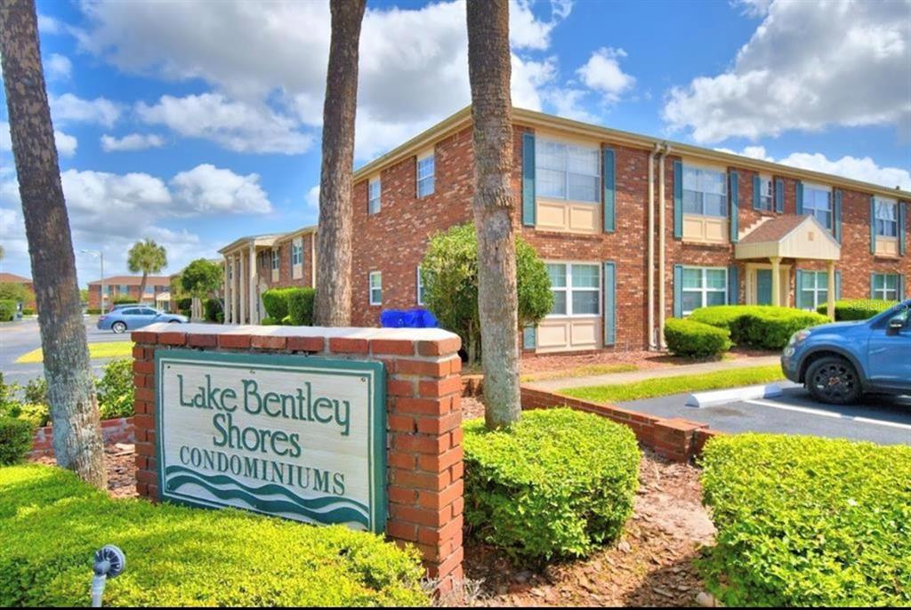 A brick sign for Lake Bentley Shores Condominiums stands in front of a two-story brick building — 1920 E EDGEWOOD DRIVE UNIT I4, LAKELAND, FL