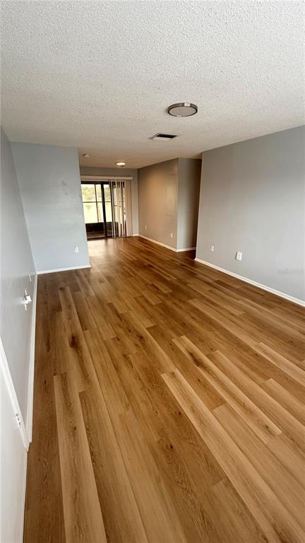 An empty living area features light wood-look flooring and light gray walls — 1920 E EDGEWOOD DRIVE UNIT I4, LAKELAND, FL