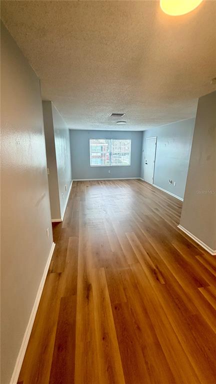 An empty living room features light gray walls, wood-look flooring, and a single window — 1920 E EDGEWOOD DRIVE UNIT I4, LAKELAND, FL