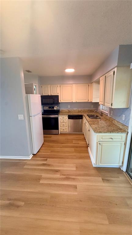 A kitchen features light-colored cabinets, granite countertops, stainless steel appliances, and wood-look flooring — 1920 E EDGEWOOD DRIVE UNIT I4, LAKELAND, FL