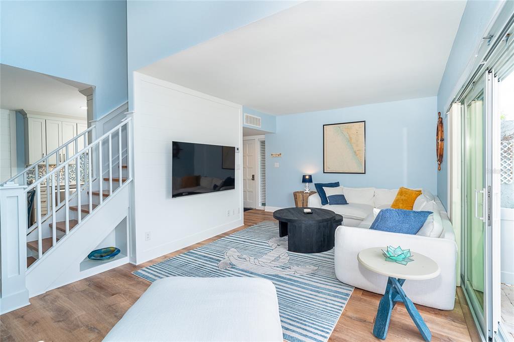 A living room features light blue walls, a white shiplap accent wall, and a staircase — 6005 N BEACH ROAD UNIT 16, ENGLEWOOD, FL
