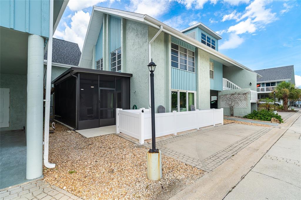 A two-story building with light blue siding, a screened-in porch, and a white privacy fence — 6005 N BEACH ROAD UNIT 16, ENGLEWOOD, FL
